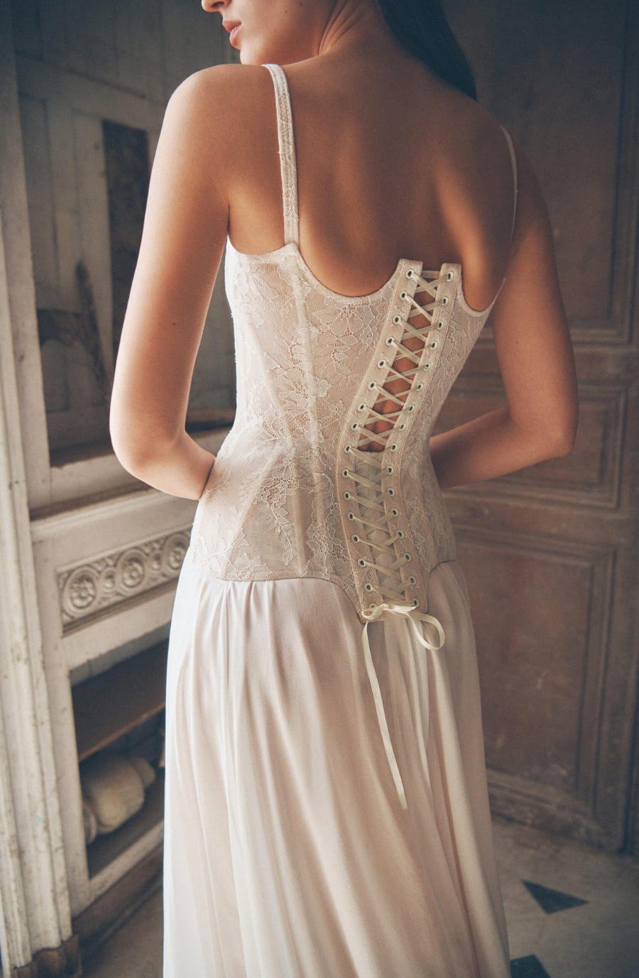 model is wearing a sleeveless spaghetti strap a-line wedding dress with a basque waist