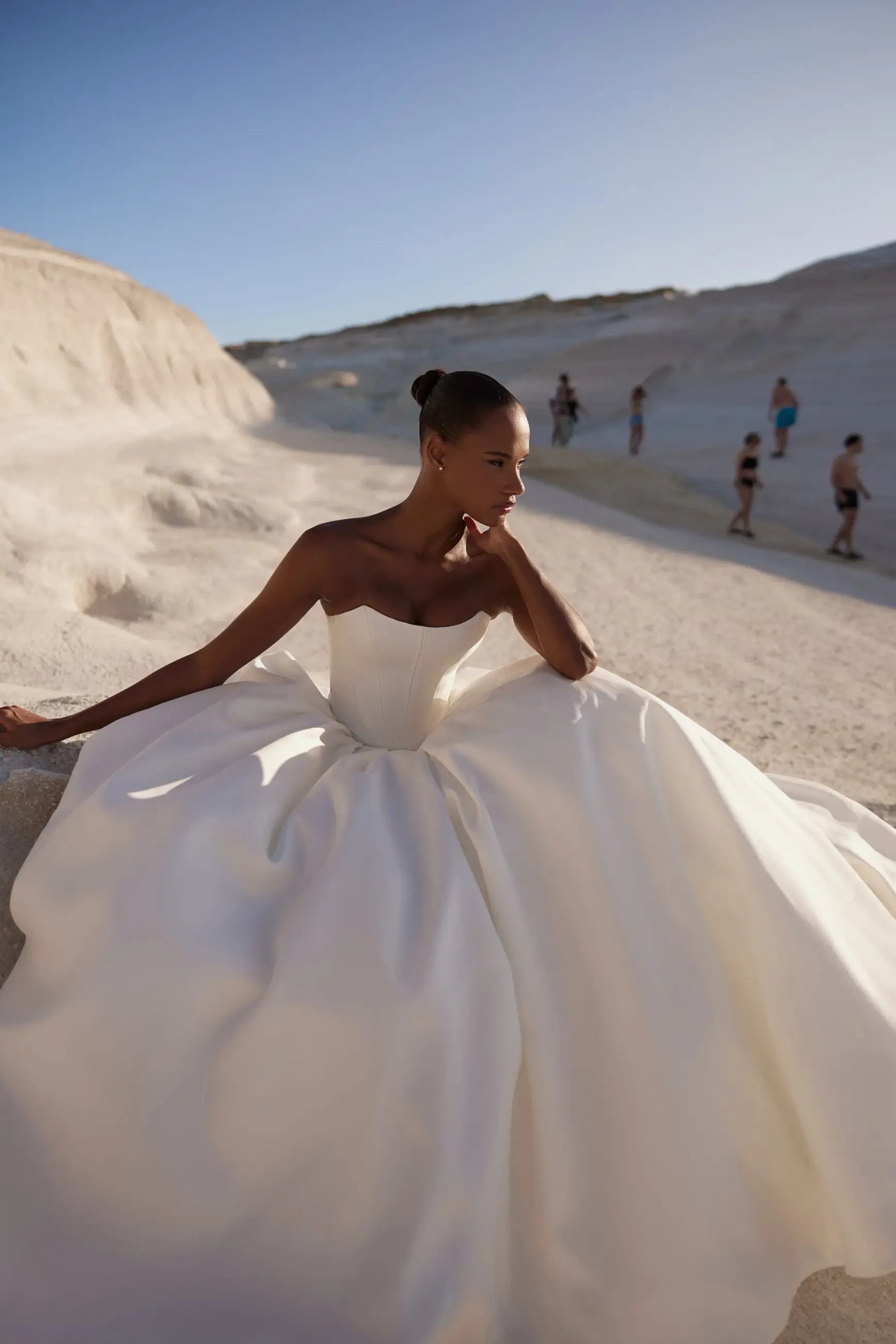 Model is wearing a strapless ball gown wedding dress with sleek fabric