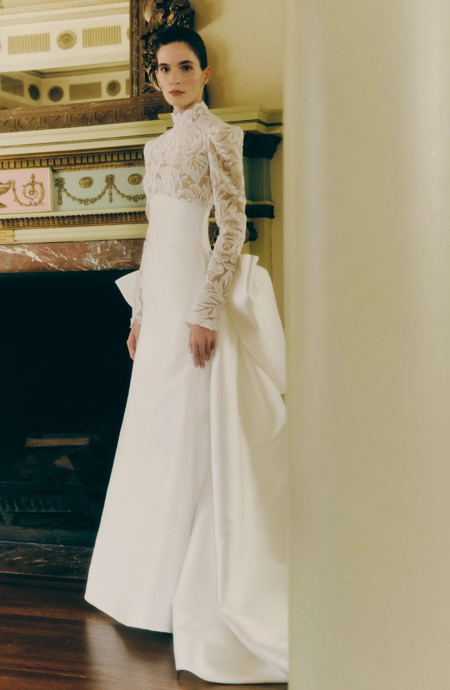 model is wearing a high neck long sleeve ball gown with an open back