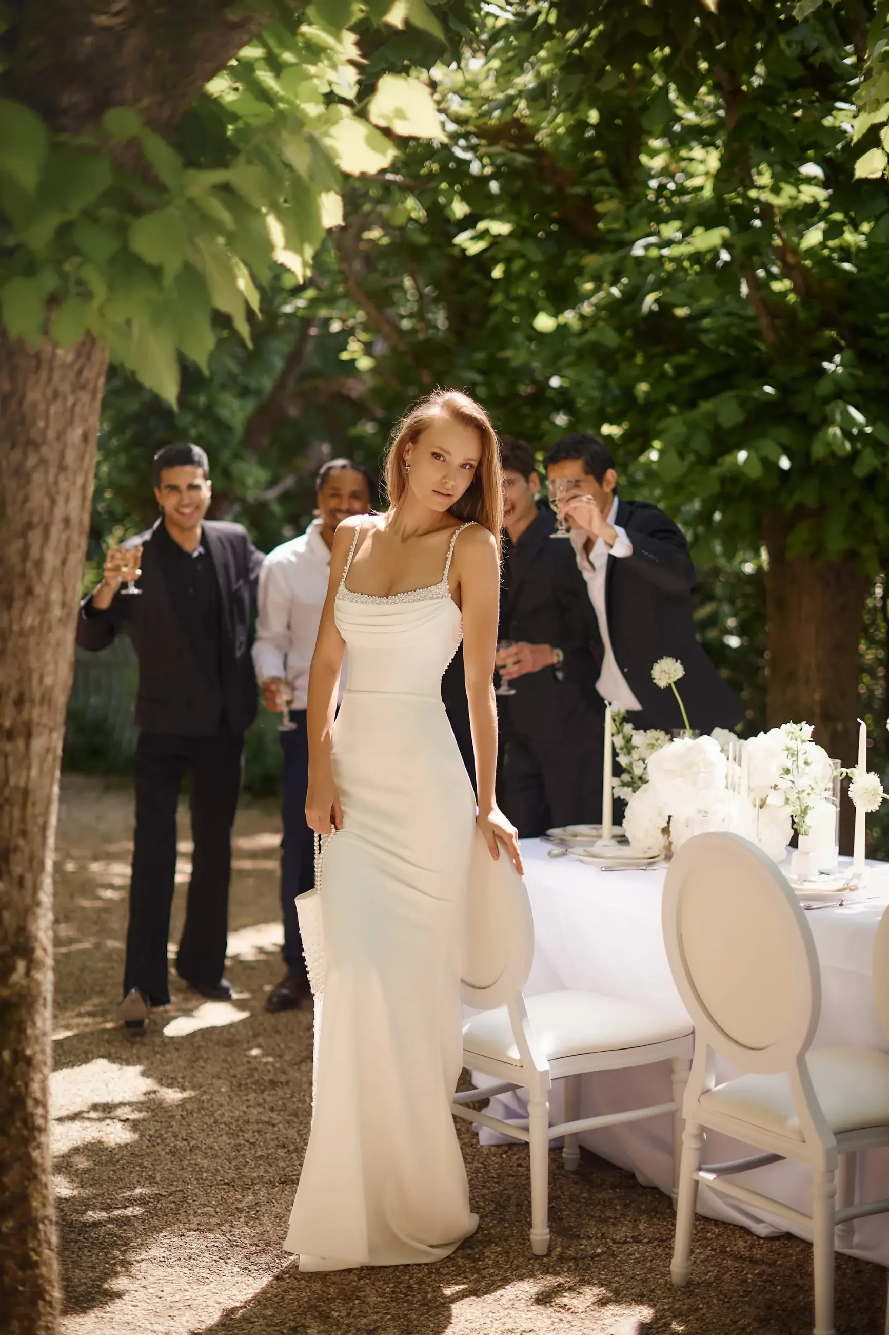 model is wearing a sleeveless sheath wedding dress